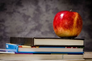 Et billede af nogle bøger med et æble ovenpå.