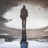 Fotoet viser en mand spejle sig. Siden handler om flashabak og påtrængende minder. Fotoet er af Randy Jacob.