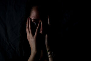 Fotoet viser en kvinde i mørke. Siden handler om en grundlæggende følelse af ikke at være god nok. Fotoet er taget af Melanie Wasser.